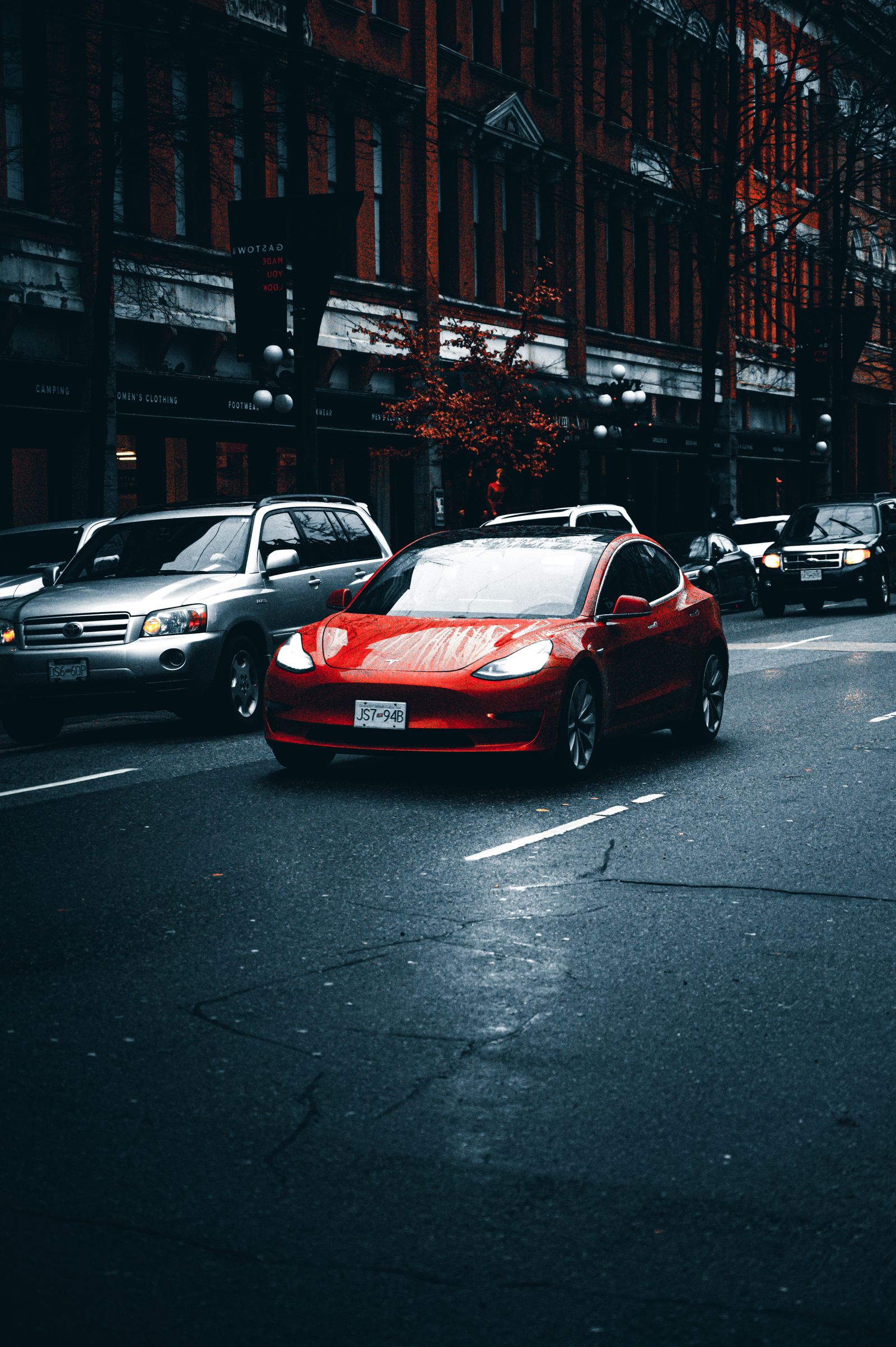 A red Tesla Model 3 parked on a city street